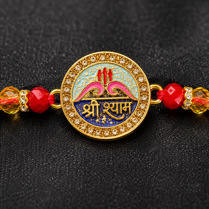A gold-plated circular Lakshmi charm bracelet with red beads and yellow crystal spacers, set against a textured black background.
